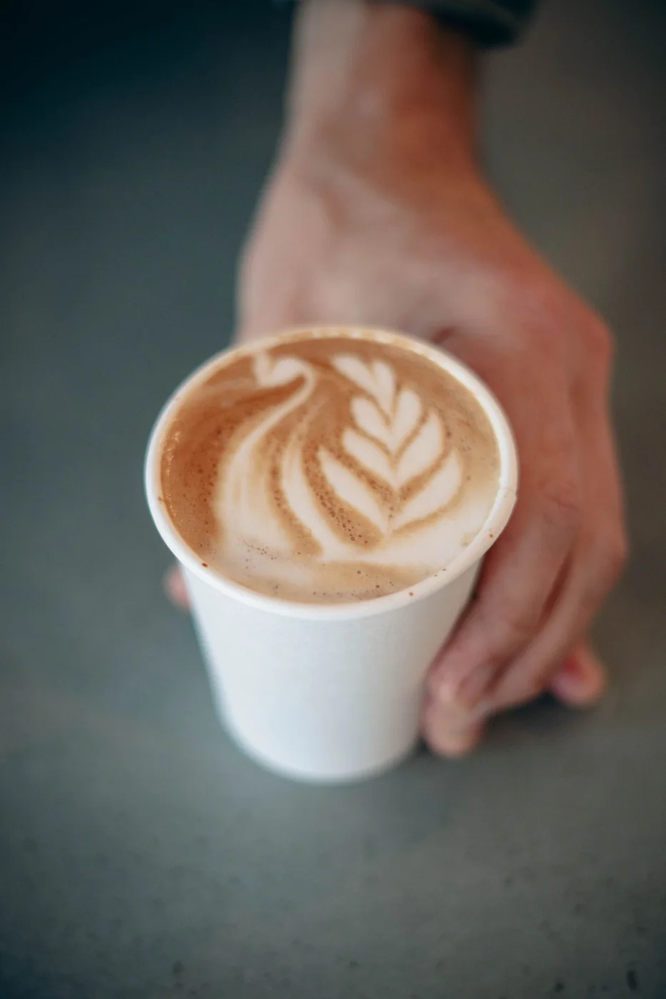 Handcrafted latte with rosetta latte art served in a to-go paper cup